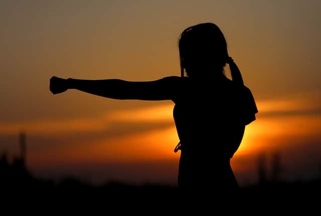 strong woman throwing punch at sunset