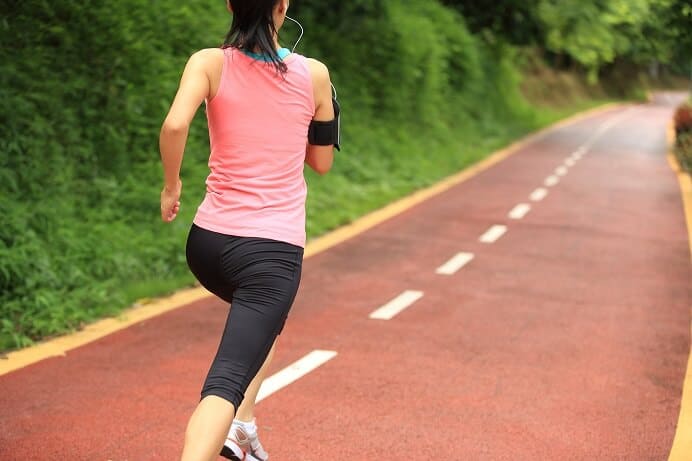 woman running along beautiful path with green scenery