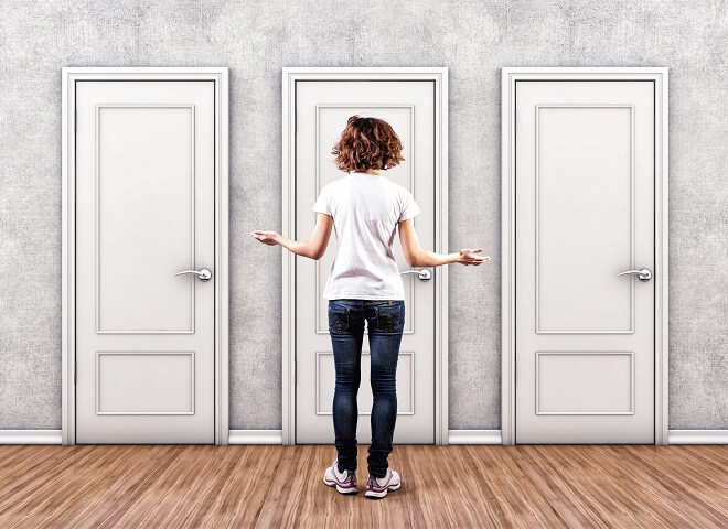 woman standing in front of three doors stressed with too many choices