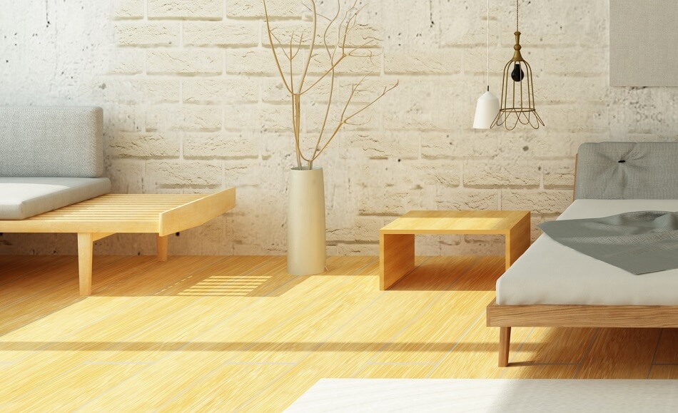 clutter-free bedroom with bed, table, planter, seat on wood floor with white brick wall