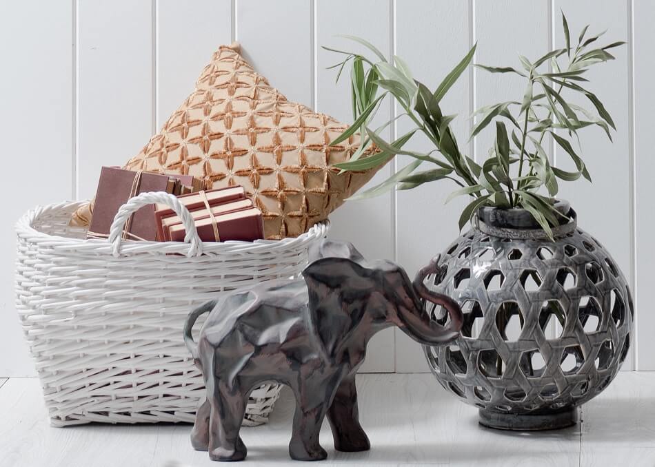 decorations to be decluttered - elephant statue, planter, basket with pillow and books against white wall