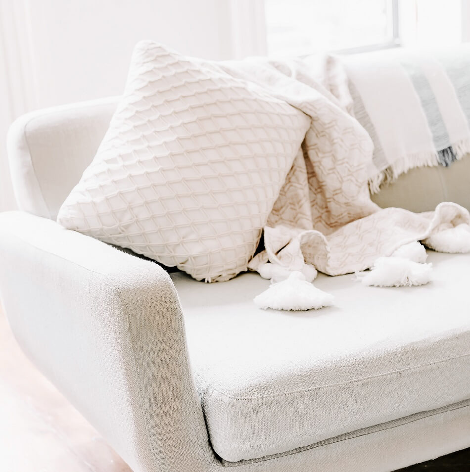 bright room with white couch pillow and blanket ready for a lazy day