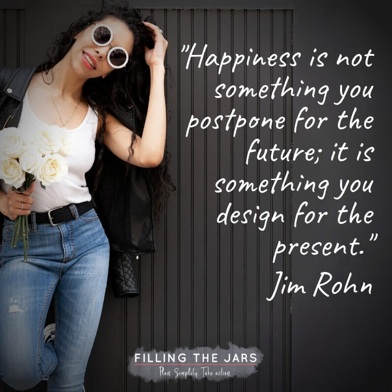 Woman in jeans and white shirt holding white flowers against black background with text overlay quote jim rohn happiness.