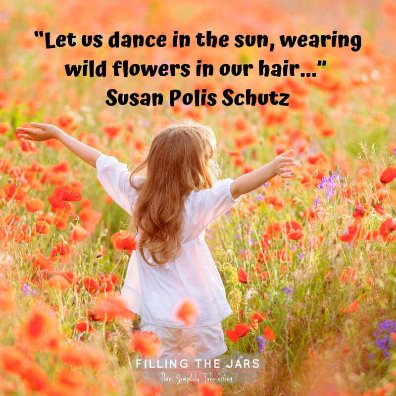 Little girl standing in field of wildflowers with text overlay quote susan polis schutz dance in the sun.