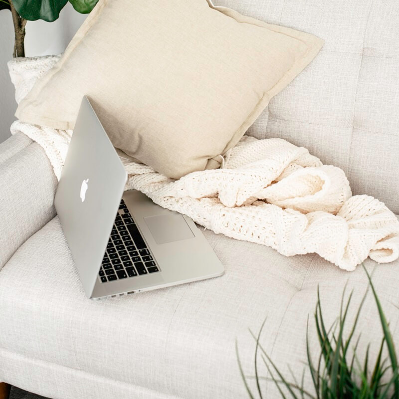 laptop and blanket left on white couch after owner got up and decided to stop being lazy