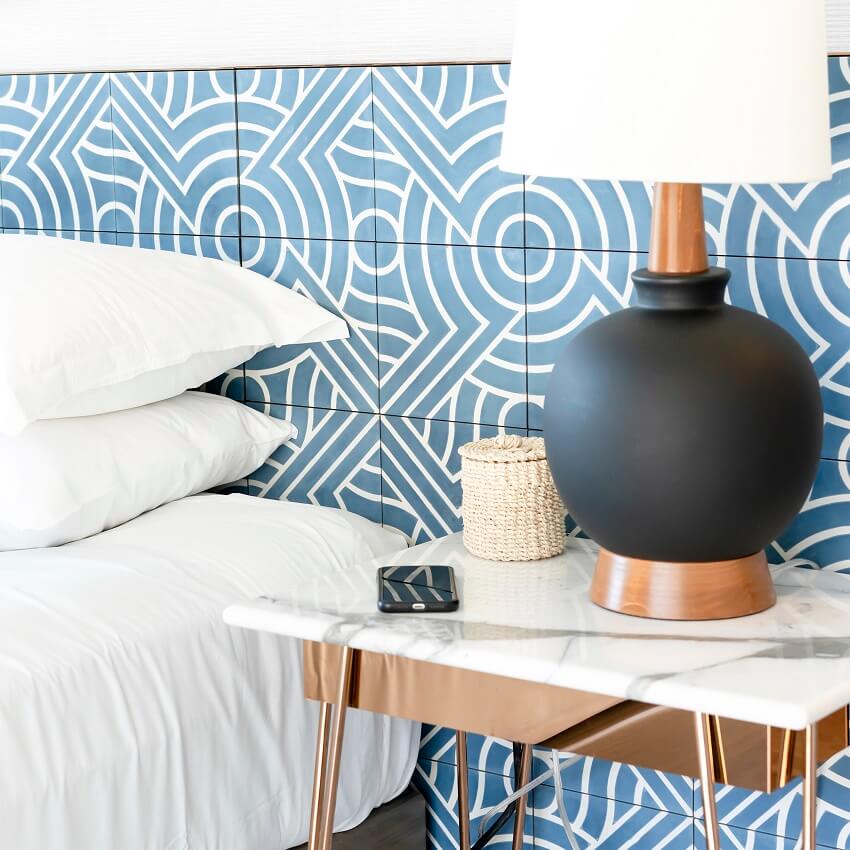 clutter-free bedroom with blue and white tile wall and lamp with black base on tidy bedside table