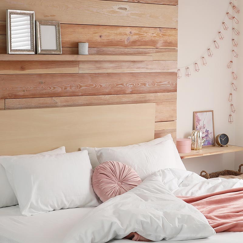 clutter-free minimalist bedroom wood and white walls white bedding peach accents wood shelf