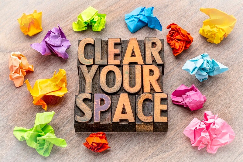 wood blocks spelling clear your space surrounded by colorful crumpled paper on wood background