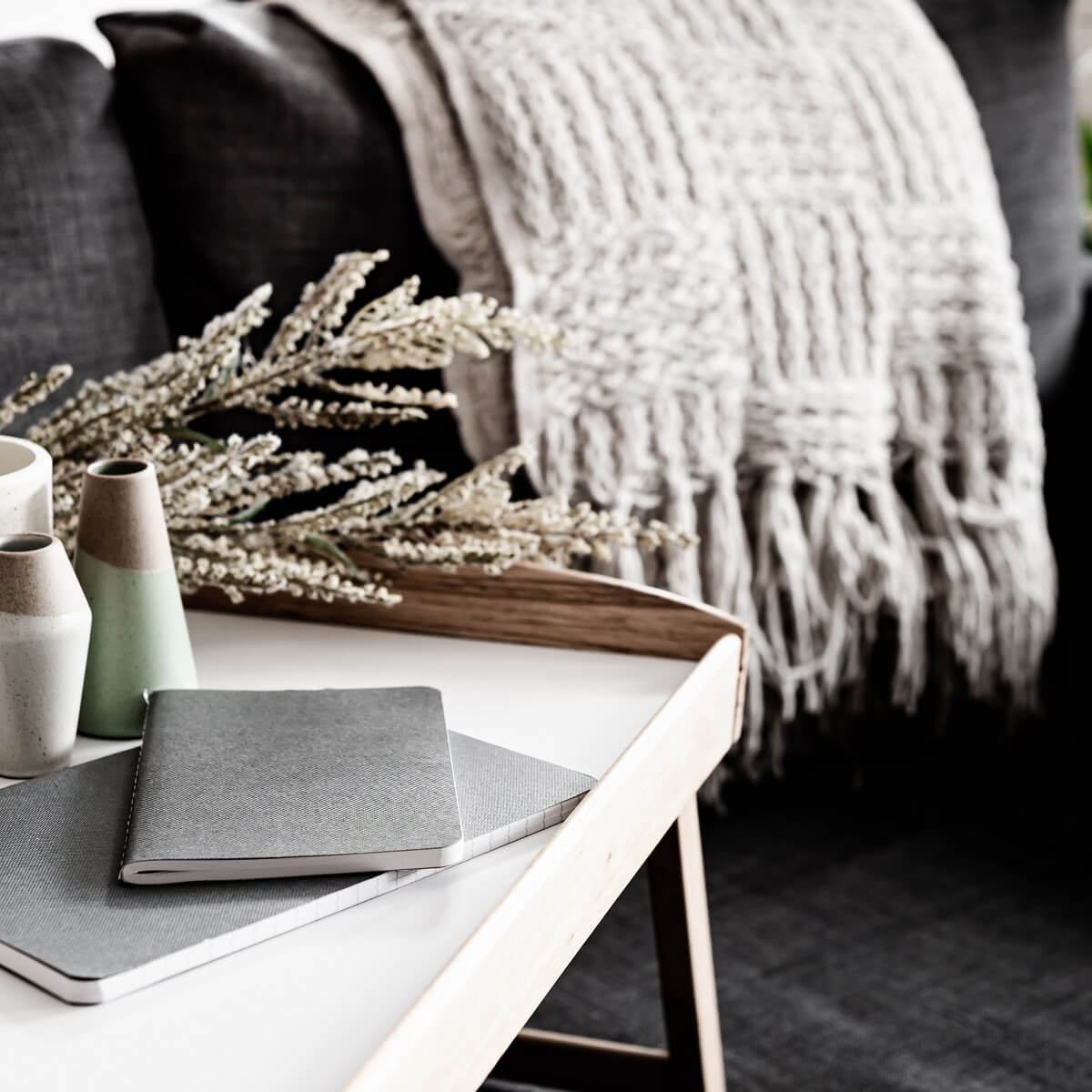 gray journals stacked on white table with background of gray couch and white blanket