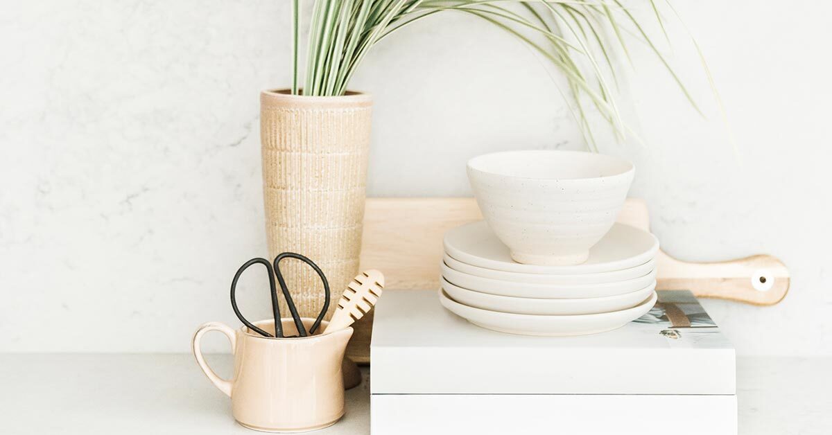 white dishes and books sitting on white shelf with other household objects