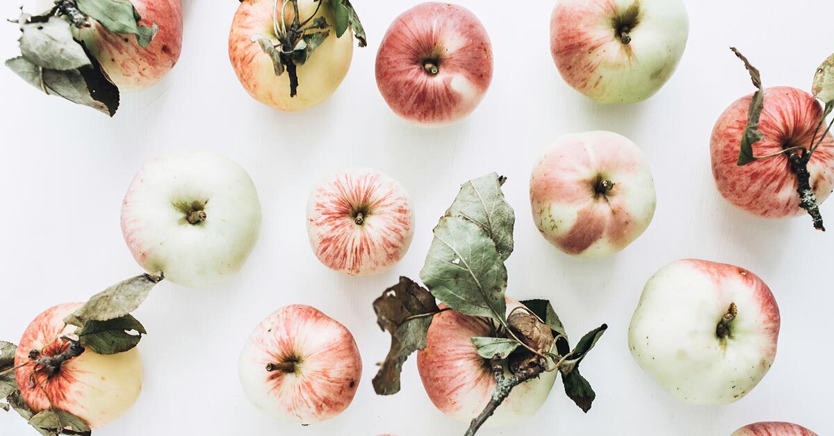 pale ripe apples scattered across white background