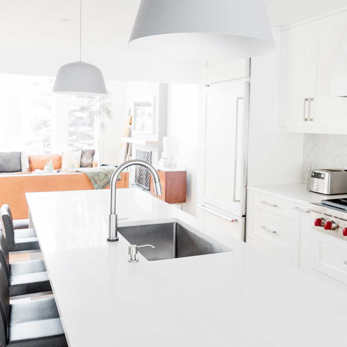 white kitchen with stainless sink and black bar stools