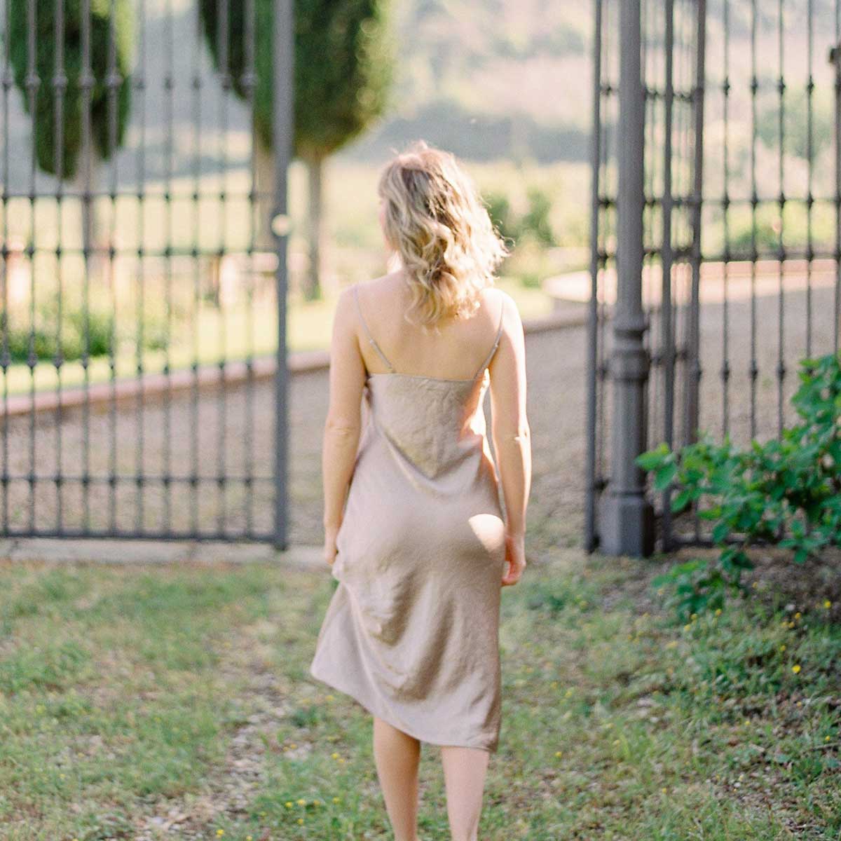 young blonde woman walking away toward black iron gate