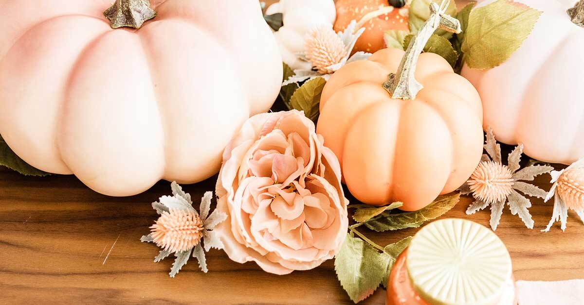 pale orange pumpkins and flowers with greenery lying on wood table