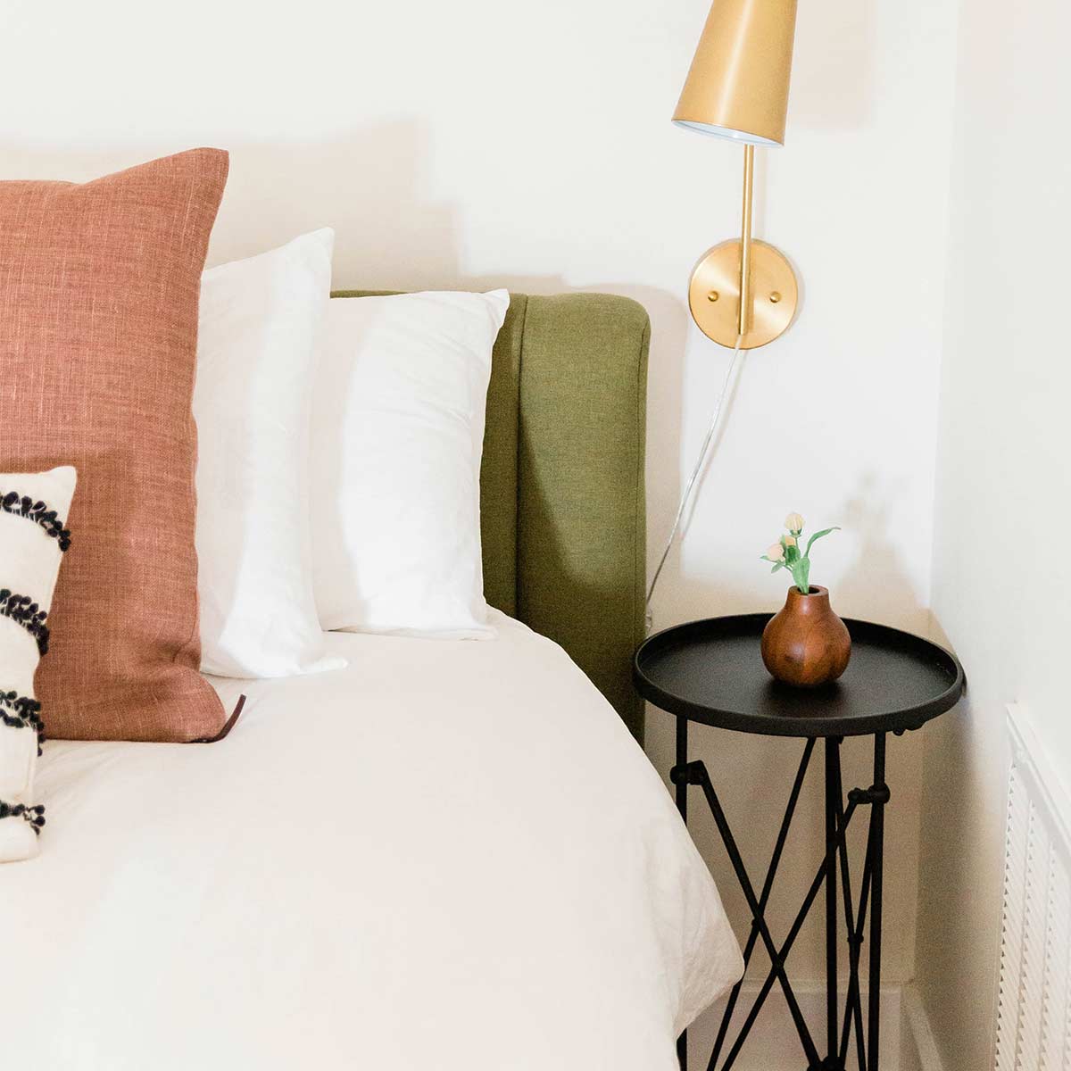 bed with decorative pillows and simple black side table in white bedroom