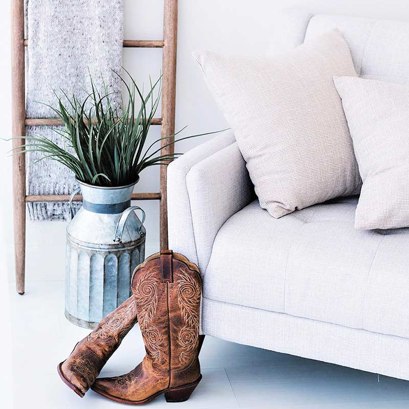 white living room with white couch, blanket ladder, rustic metal milk can, brown cowboy boots