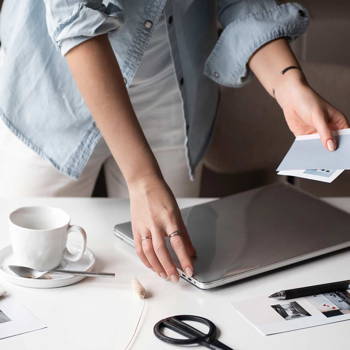 woman in light blue shirt decluttering white desktop