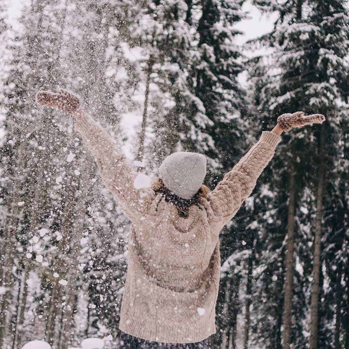 woman in hat and pink sweater enjoying an intentional life outdoors in the snow