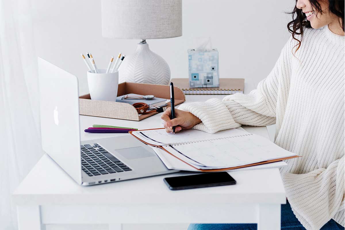 woman wearing white sweater working at desk in white home office