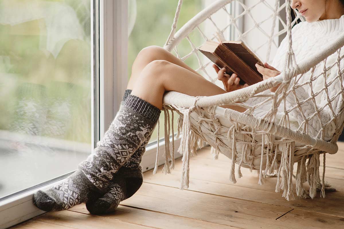 woman sitting in swing chair next to sliding doors while reading