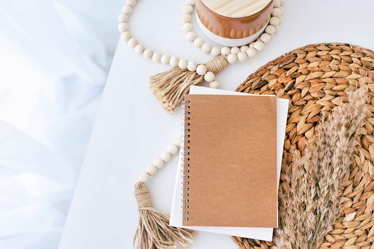 Journal, notebook, and decorative items on white desk.