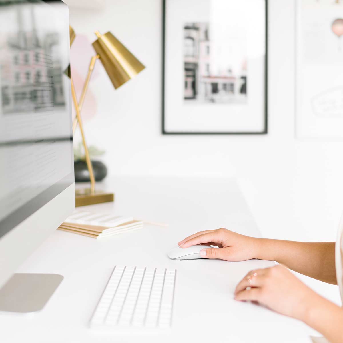 Side view of woman's hands working on desktop computer in white office.