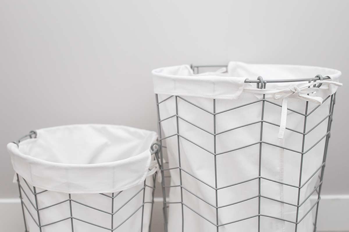 Two wire bins with fabric liners against white wall.