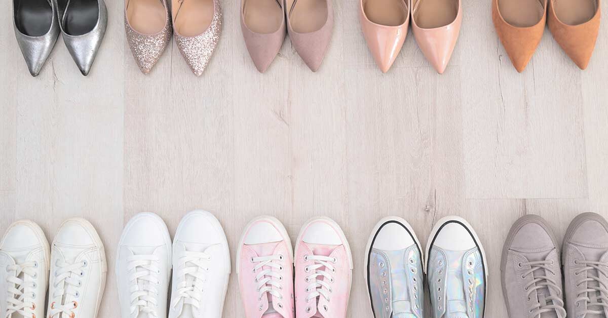Several pairs of shoes lined up on wood floor with heels at top and sneakers at the bottom.