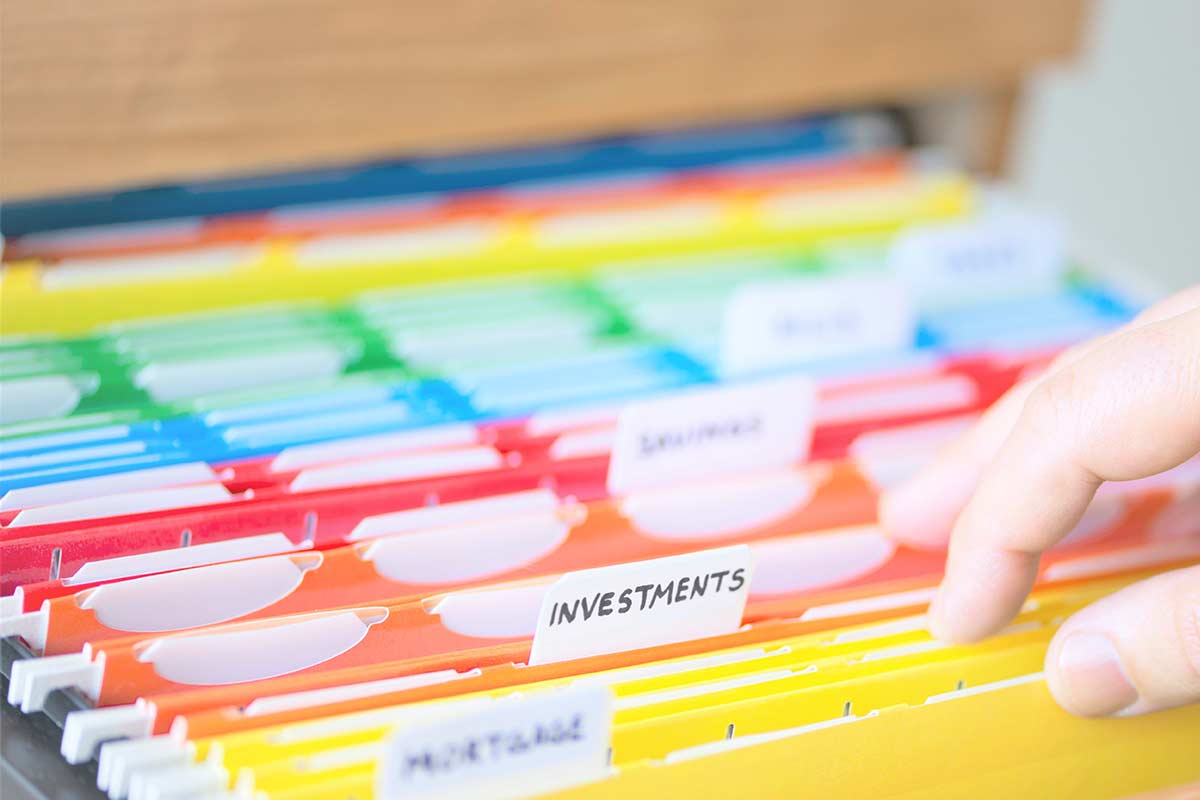 Adult hand flipping through colorful organized hanging file folders.