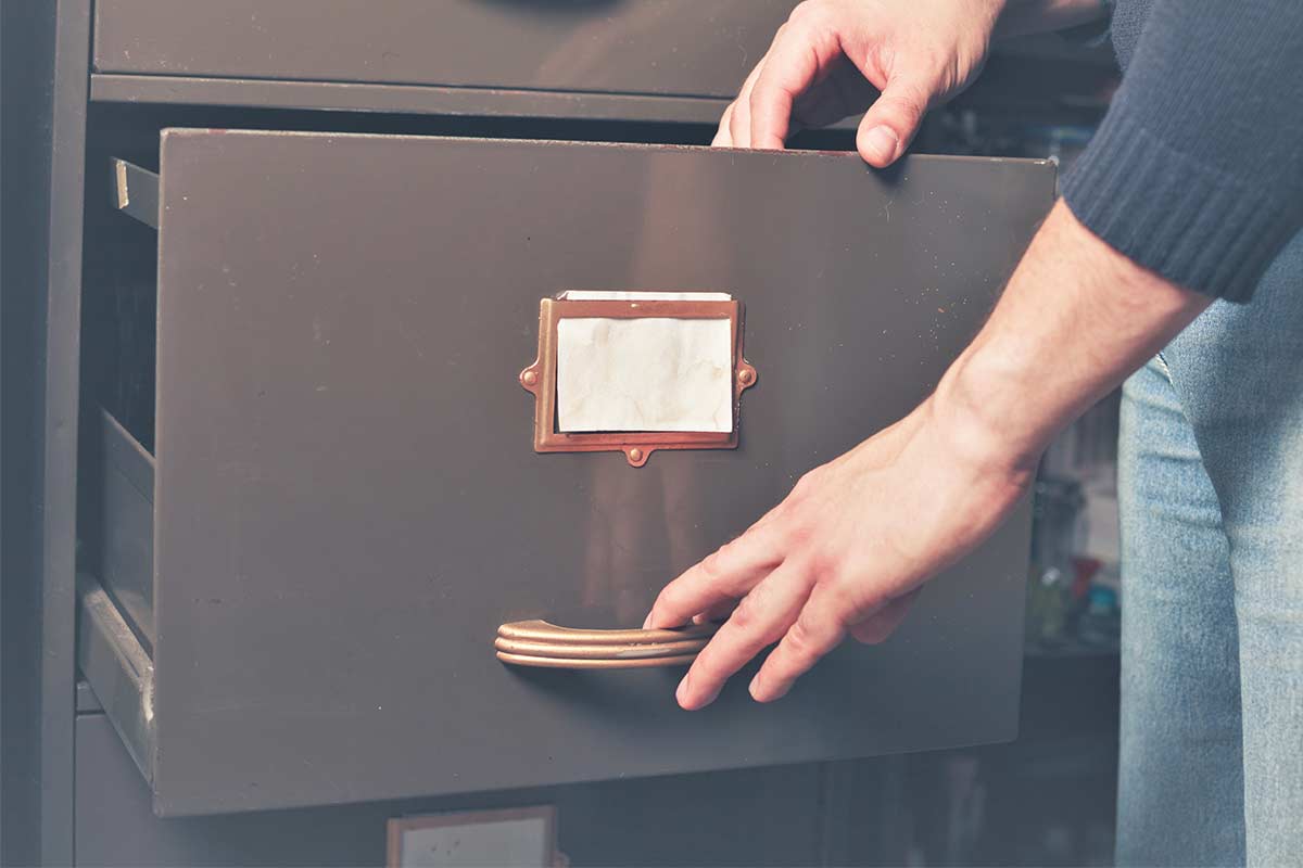 Adult opening drawer of large old filing cabinet.