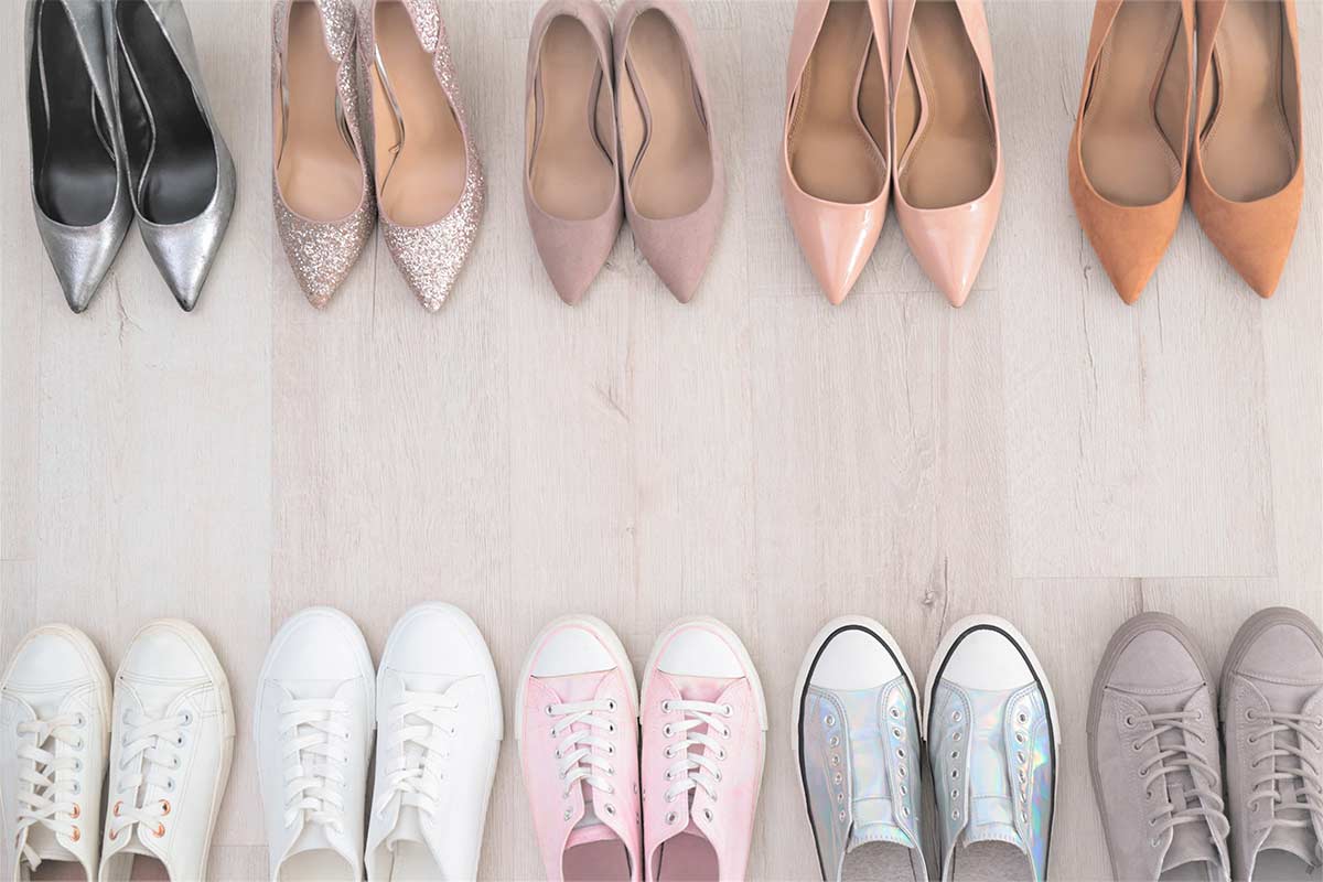 Several pairs of decluttered shoes lined up on wood floor with heels at top and sneakers at the bottom.