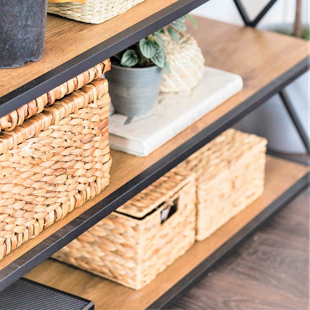 Plants and wicker baskets for storing clutter on wood shelves.