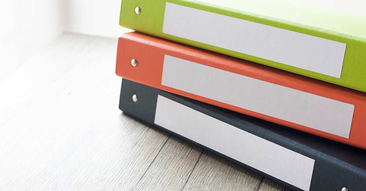 Stack of paper organizing binders on wood table.