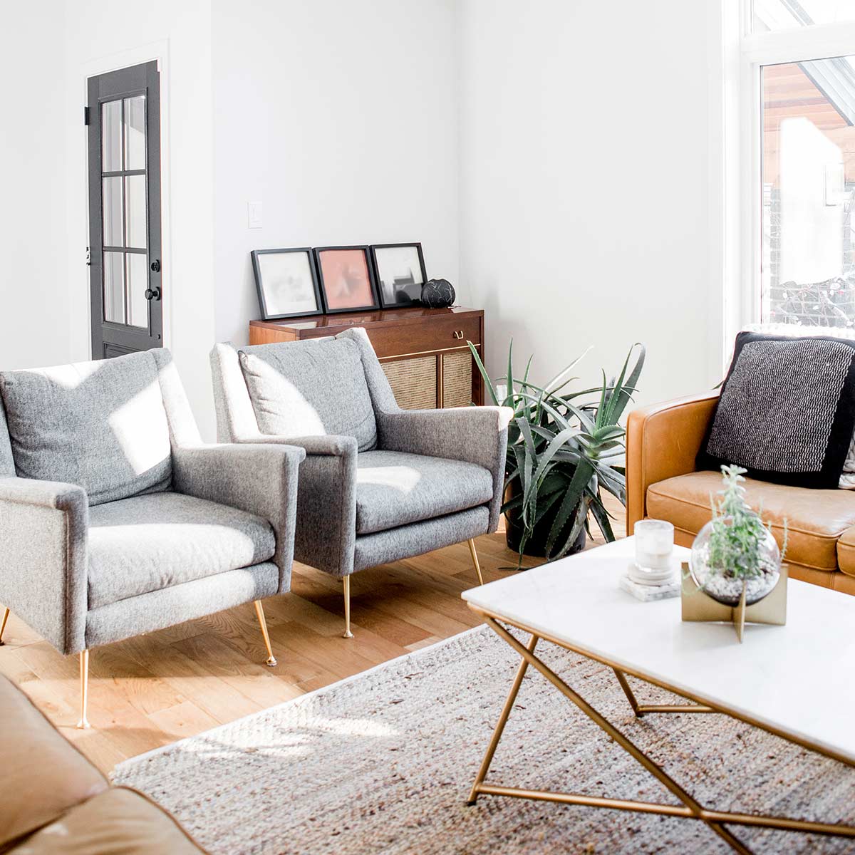 Simple white living room with grey and leather furniture.