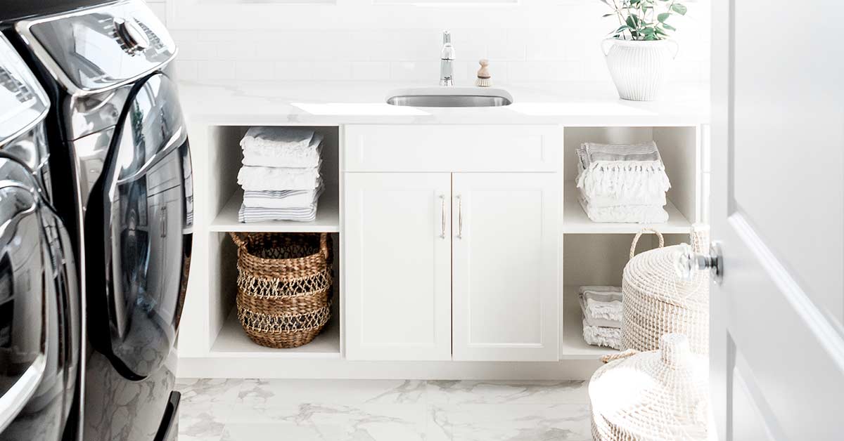 Beautiful white laundry room with black washer and dryer.