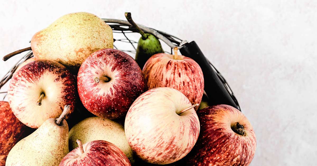 Top view of apples and pears in mesh bowl on white counter - perfect to welcome fall.