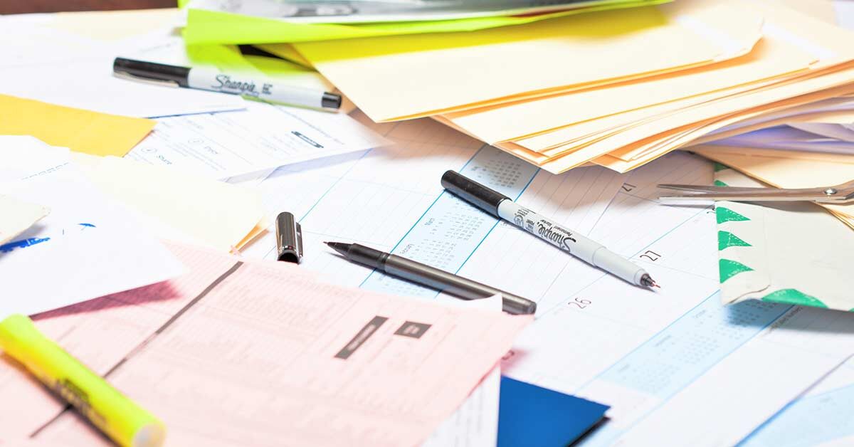 Messy papers and markers on desk that need to be organized.