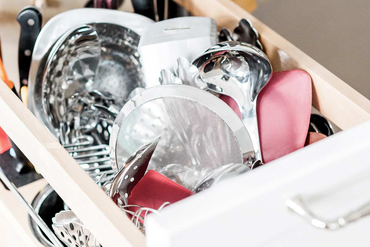 Open utensil drawer in kitchen that needs to be decluttered.