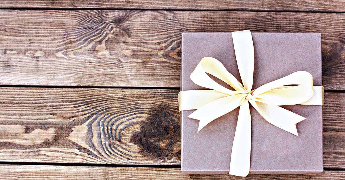 Wrapped gift for writer with creamy ribbon on rustic wood background.