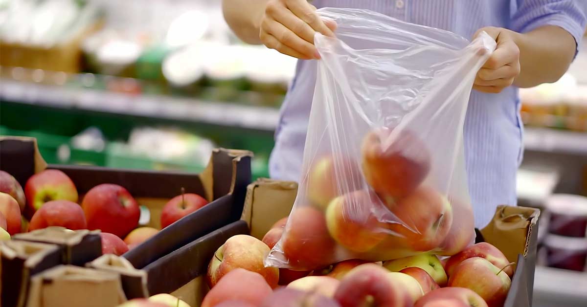 Woman in blue shirt choosing fruit while she does a once a month grocery shop.