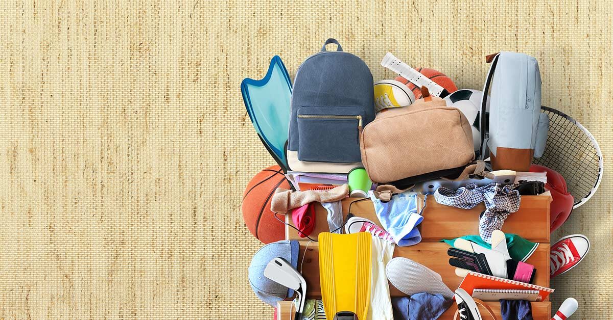 Too much stuff piled on dresser and in drawers against woven-look grass cloth background.