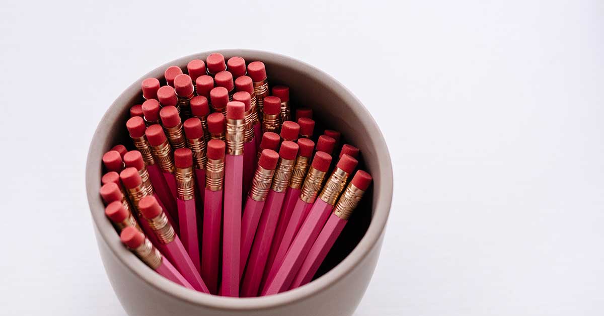 Cup full of pink pencils on white background ready to use for creative writing prompts about love.