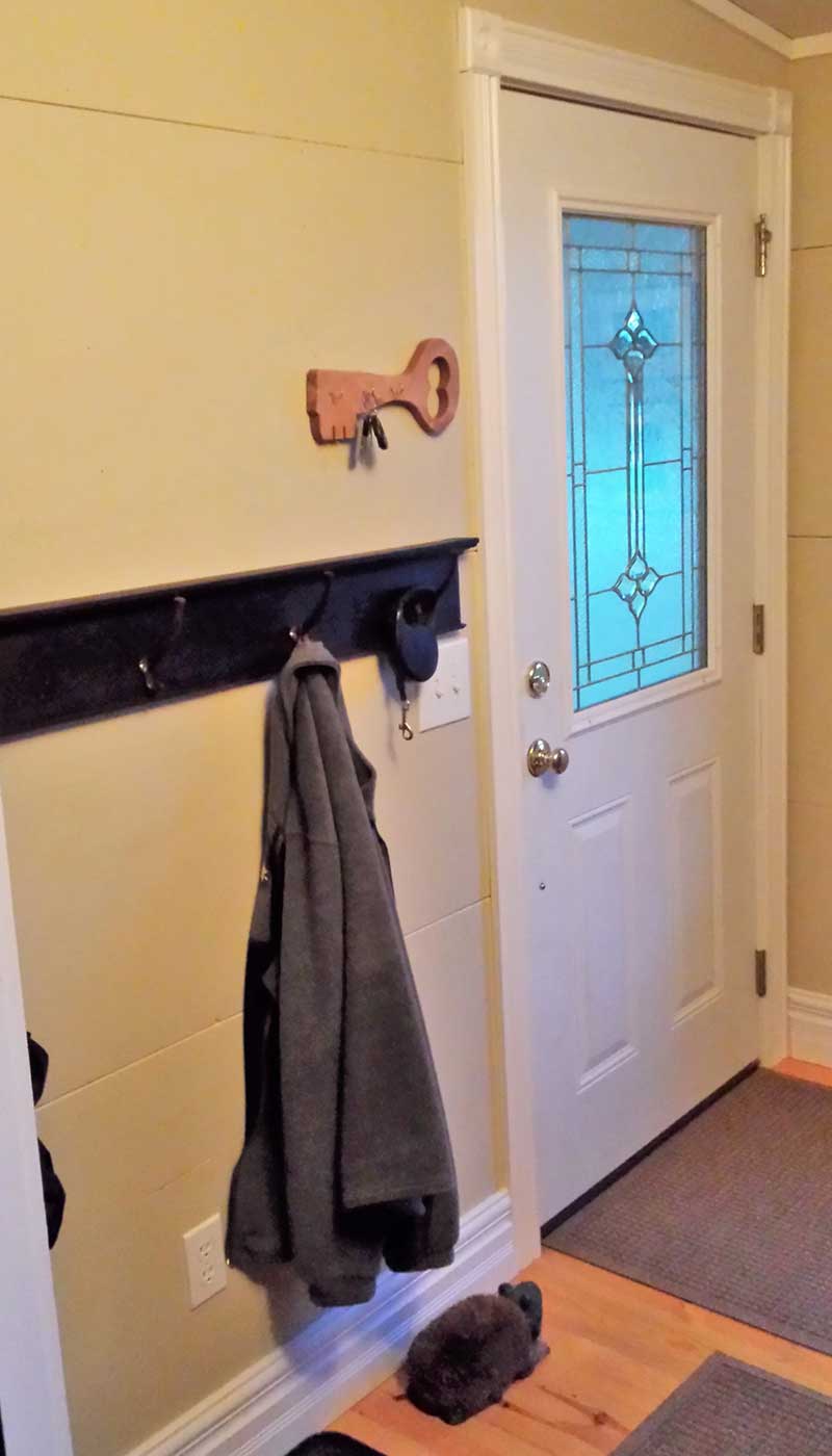 DIY entryway mudroom improvement in progress with front door and coat rack.