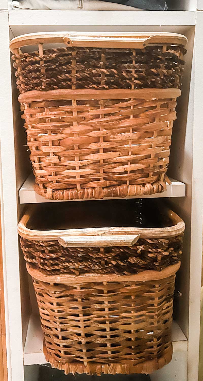 Two wicker baskets in white cube storage unit in no-dresser bedroom closet.