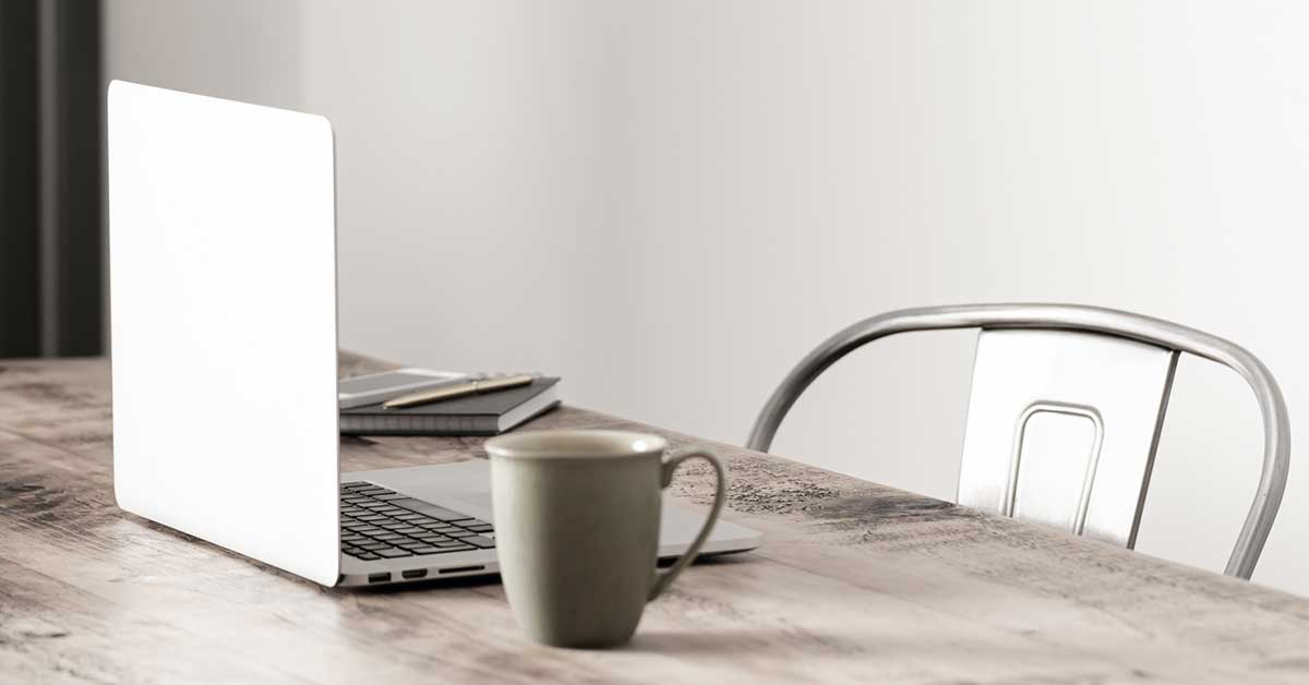 June morning creative writing tableau with coffee mug and laptop on rustic table.