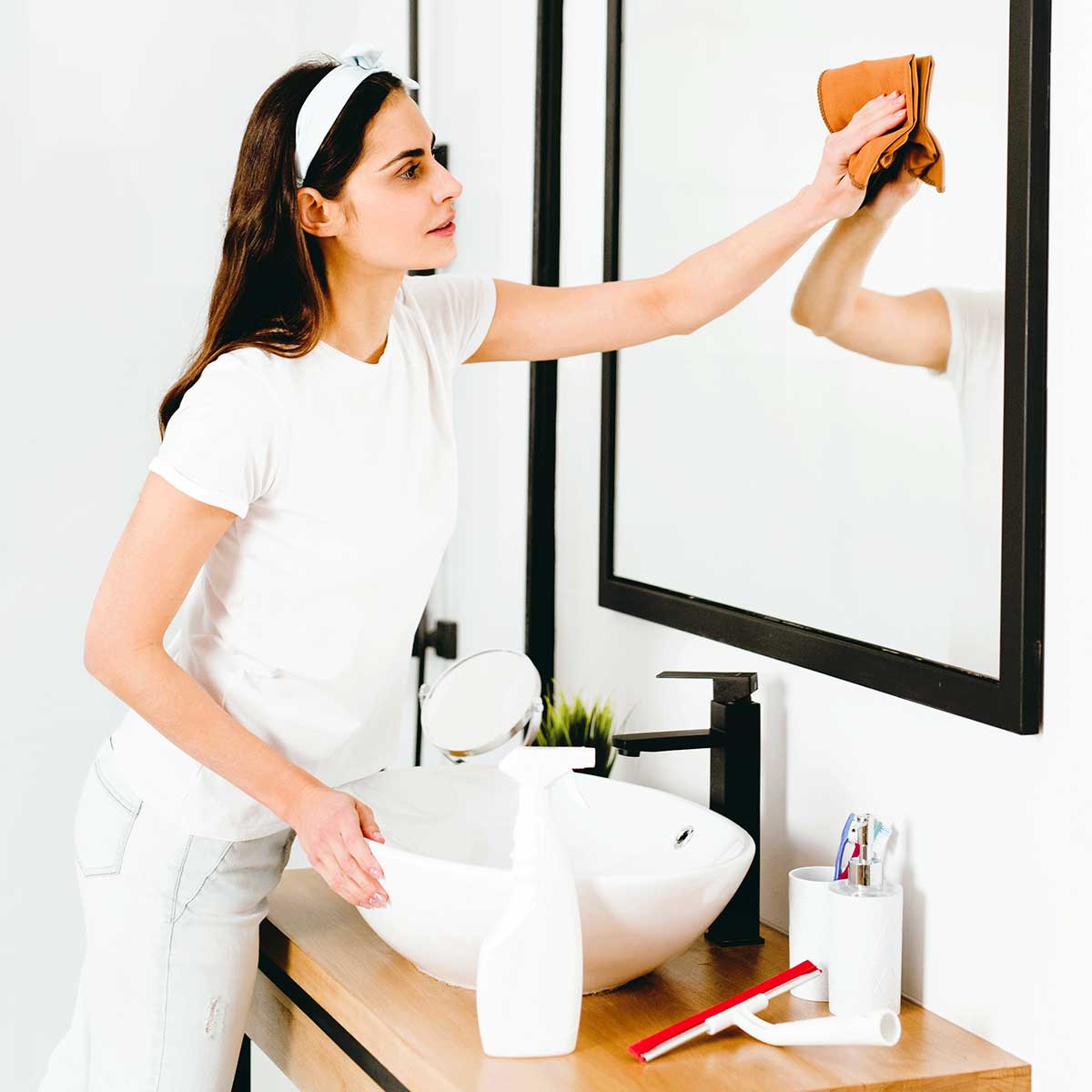 Woman cleaning bathroom mirror.