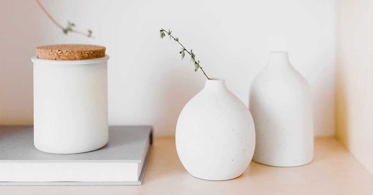 Clean white vases and grey book on dust-free shelf.