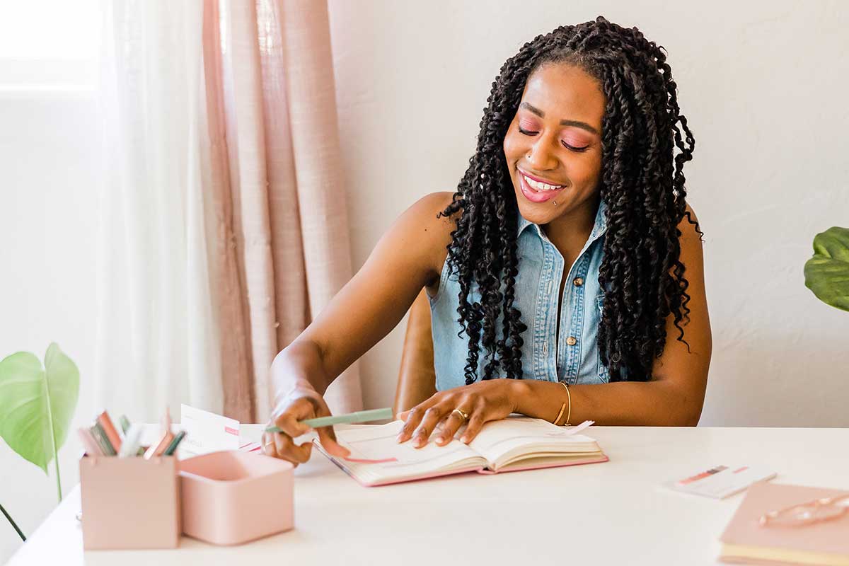 Black woman sitting at desk and planning for the month.