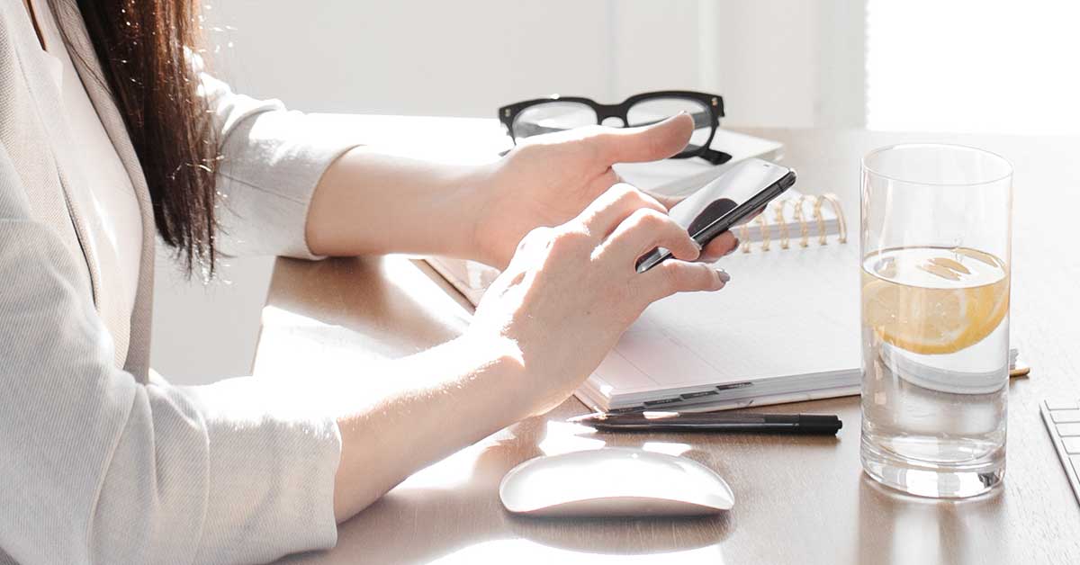 Woman sitting at table with water and planning tools preparing for a productive weekend life management session.