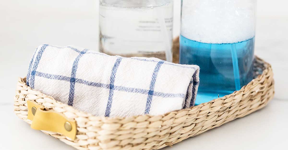 Cleaning sprays and towel in wicker basket.